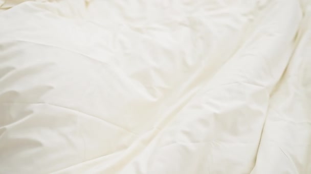Een jonge vrouw slaapt rustig in een gezellige slaapkamer, omhuld door zacht wit beddengoed. - Video