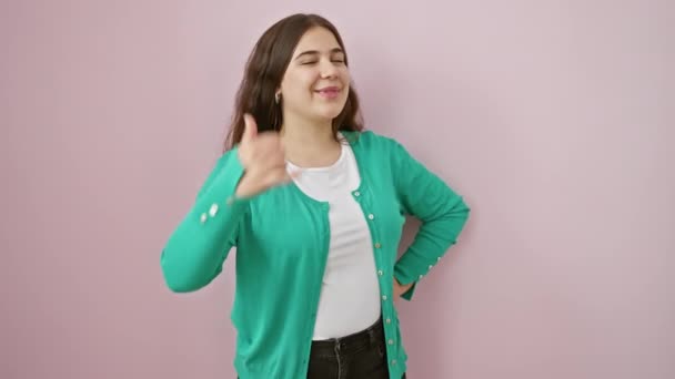 Vidám fiatal spanyol nő, hogy telefon gesztus ujjaival, mosolygó széles rózsaszín elszigetelt háttér, boldog kifejezés kommunikáló barátságos koncepció - Felvétel, videó