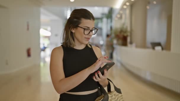 Superbe femme hispanique rayonnant de bonheur, tenant le téléphone dans le salon de l'hôtel moderne, envoyant des SMS - Séquence, vidéo