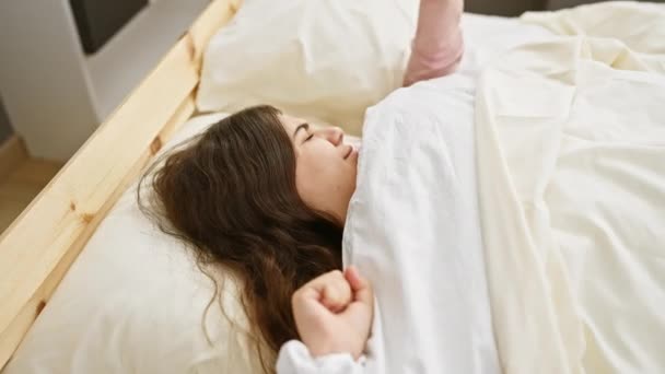Молода жінка спокійно спить у затишній спальні, її волосся розтікається на подушці. - Кадри, відео