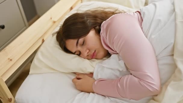 Een rustige jonge vrouw slaapt in een comfortabele slaapkamer, belichaamt ontspanning en rust in een thuisomgeving. - Video
