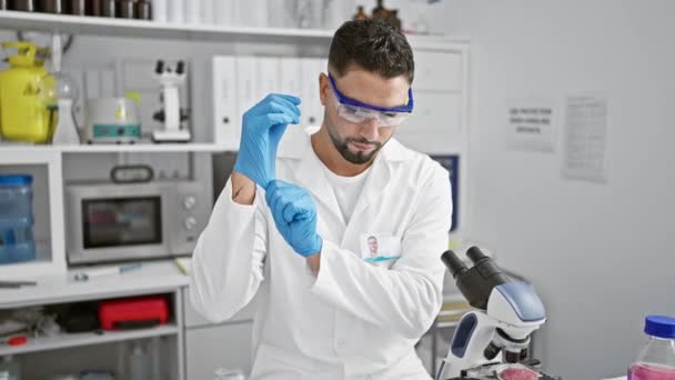 Mężczyzna w goglach laboratoryjnych i rękawiczkach bada próbki w nowoczesnym laboratorium.. - Materiał filmowy, wideo