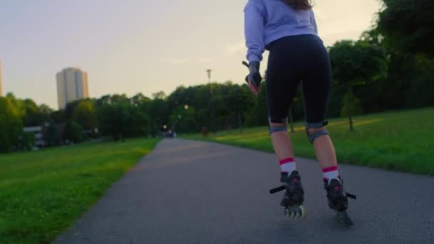 Visszapillantás felismerhetetlen fiatal nő görkorcsolyázás a parkban - Felvétel, videó