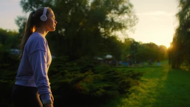 Młoda kobieta jeżdżąca na rolkach po parku podczas zachodu słońca - Materiał filmowy, wideo