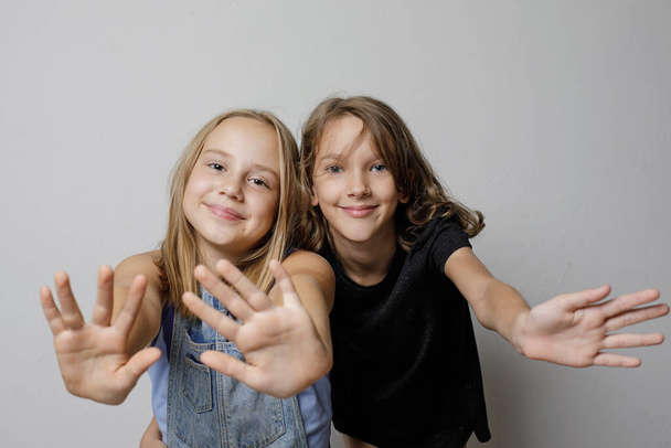 Boldog mosolygós lányok gyerekek testvérek barátok wawing kezét fehér stúdió falra banner háttér, divat portré   - Fotó, kép