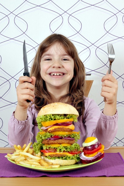 Szczęśliwa dziewczynka z dużych hamburgerów gotowy na obiad - Zdjęcie, obraz