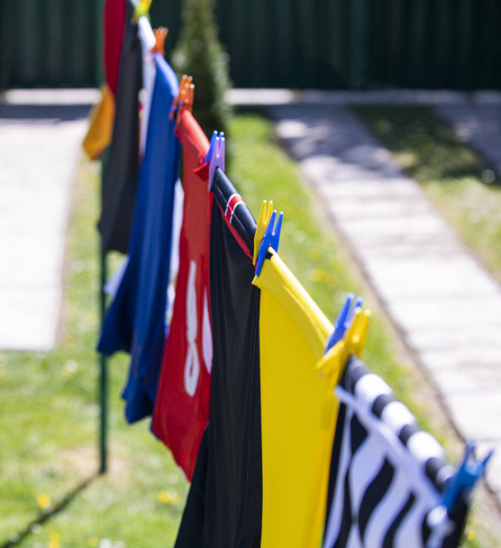 Bunte Kleider hängen zum Trocknen an einer Wäscheleine. Fußballtrikots - Foto, Bild