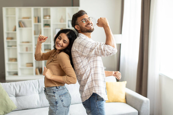 Fiatal indiai házastársak táncolnak otthon a nappaliban, pár szórakozik, élvezik az együtt töltött hétvégét otthon - Fotó, kép