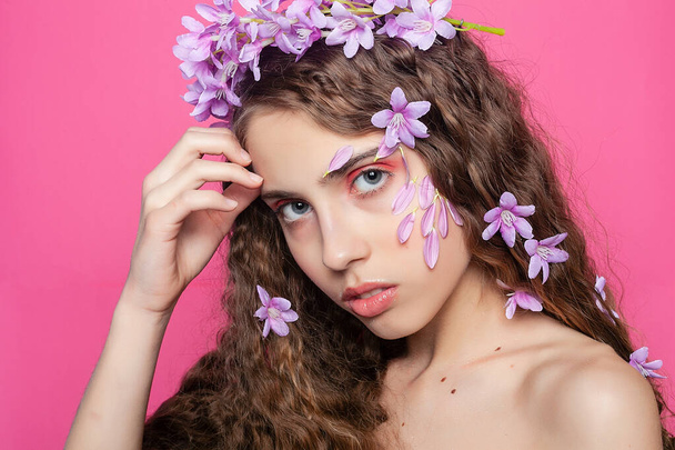 Botanical elegance: Curly-haired girl showcases her beauty with purple flowers in her hair, adding a touch of grace and sophistication - Fotoğraf, Görsel