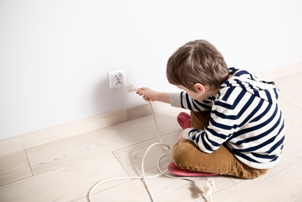Curious little boy playing with electric plug. - Photo, Image