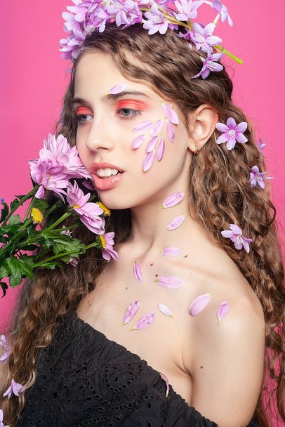 Natural beauty: Adorned with purple blooms, the girl's curly hair creates a captivating and enchanting sight, embodying floral allure - Foto, afbeelding