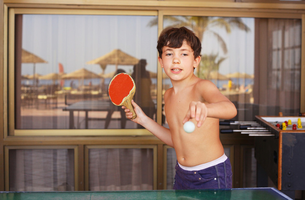 красивый мальчик играет в настольный теннис в отеле пляжного курорта
 - Фото, изображение
