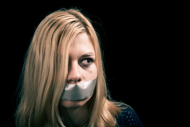 Kidnapped woman hostage with tape over her mouth - 写真・画像