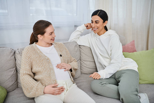 Две женщины, беременная женщина и ее тренер, участвуют в содержательном разговоре на диване во время курсов для родителей. - Фото, изображение