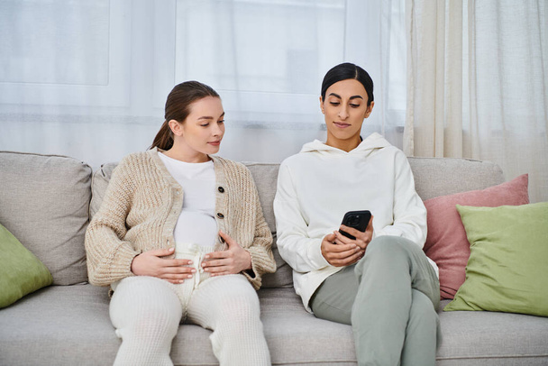 Eine schwangere Frau und ihr Trainer sitzen während des Elternkurses bequem auf einer Couch. - Foto, Bild