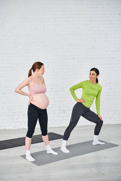 Twee zwangere vrouwen staan zij aan zij, de een coacht de ander tijdens een oudercursus, beide met kracht en eenheid.. - Foto, afbeelding