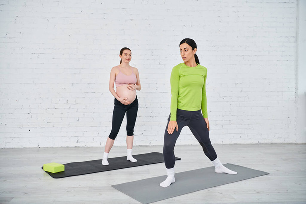 Дві вагітні жінки впевнено стоять на килимках йоги, практикуючи вправи, керовані їх тренером під час батьківських курсів. - Фото, зображення