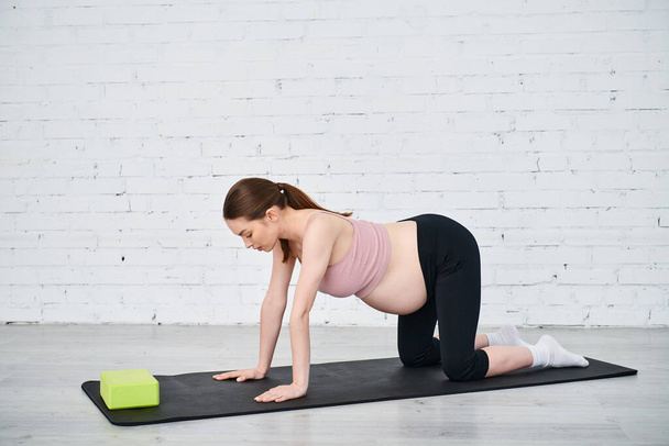 Uma mulher grávida se envolve em um exercício de prancha enquanto está sendo guiada por seu treinador durante os cursos dos pais. - Foto, Imagem