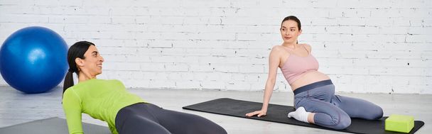 Dos mujeres, una embarazada, realizan con gracia posturas de yoga en un entorno sereno, guiadas por un instructor durante un curso de padres. - Foto, Imagen
