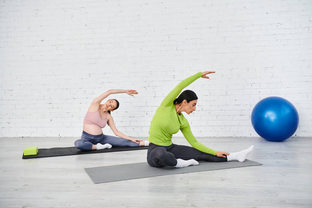 Una donna incinta pratica yoga su un tappeto mentre il suo istruttore la guida durante i corsi dei genitori. - Foto, immagini