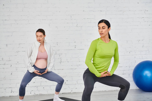 aanstaande moeder sierlijk oefenen yoga poses in de voorkant van een rustieke bakstenen muur tijdens een prenatale oefening sessie. - Foto, afbeelding