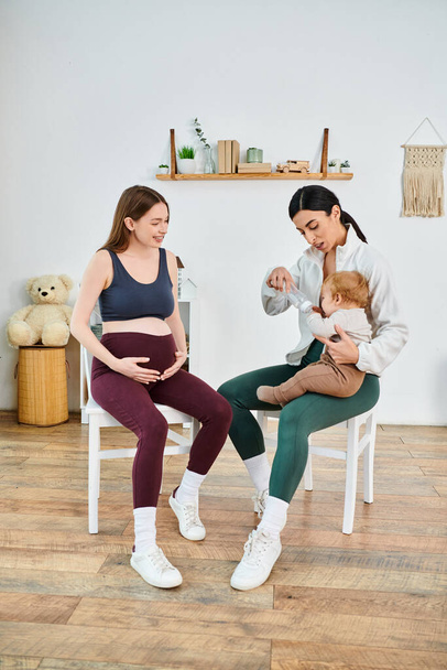Una donna incinta si siede, culla del suo neonato, ricevendo una guida da un allenatore in un corso per genitori a casa.. - Foto, immagini