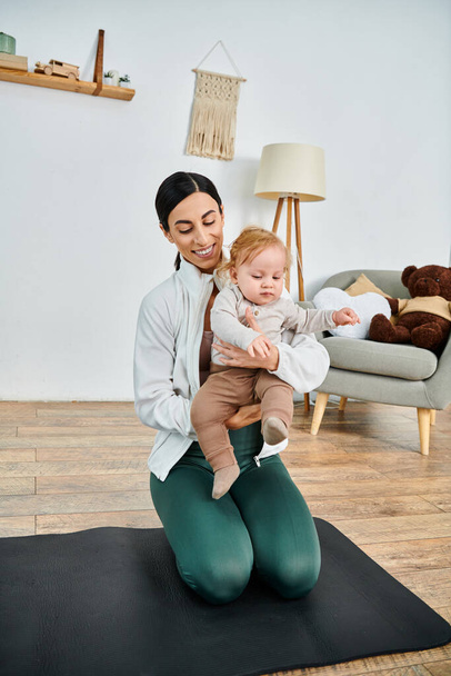 Молодая мать сидит на коврике для йоги, мирно держа своего ребенка, получая руководство от своего тренера во время курса для родителей. - Фото, изображение