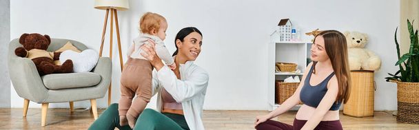 Egy fiatal, gyönyörű anya ül a padlón, óvatosan ringatja a babáját, miközben útmutatást kap egy szülői tanfolyamon.. - Fotó, kép