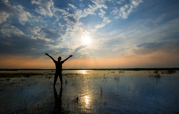 Homme tenant les bras vers le haut dans la louange au coucher du soleil tout en étant dans l'eau
 - Photo, image