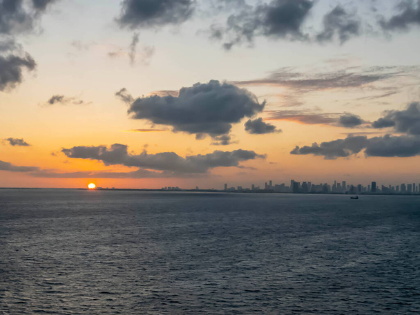 Während die Sonne über der Küste Miamis untergeht, legt ein Kreuzfahrtschiff anmutig ab und begibt sich auf ein karibisches Abenteuer, das ein goldenes Licht auf die ruhige See wirft - Foto, Bild