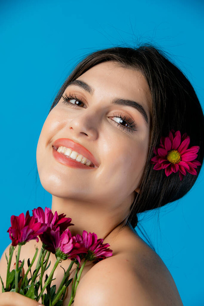 Portret van een vrolijke, mooie dame, model met fotoshoot met bloemen, glimlachend, kijkend naar de camera. Het begrip schoonheid. - Foto, afbeelding