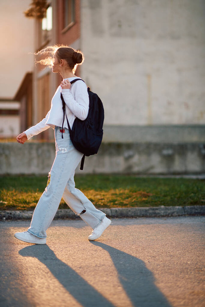 美しいヨーロッパのティーンエイジャー, サイドプロファイルの肖像画で撮影, 学校の後に日没の間に家を歩く, 彼女のバックパックを運ぶ. - 写真・画像