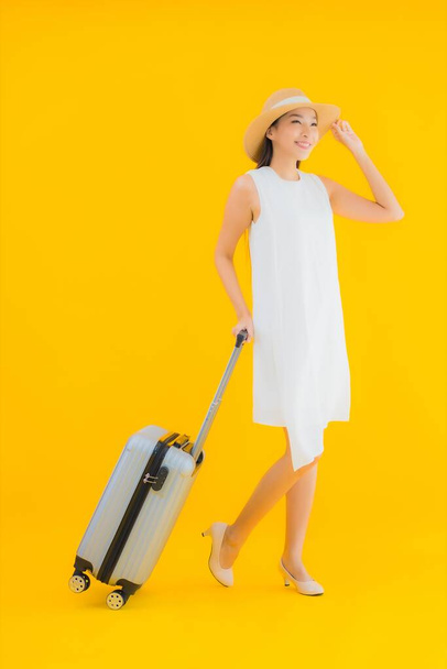Retrato hermoso joven asiático mujer viaje concepto con equipaje en amarillo aislado fondo - Foto, imagen