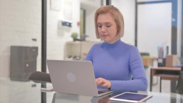Νεαρή γυναίκα με πονόδοντο που εργάζεται σε φορητό υπολογιστή στο γραφείο - Πλάνα, βίντεο