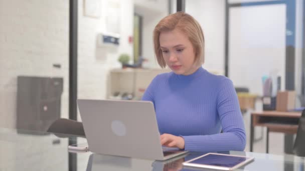 Молода жінка шокована втратами на ноутбуці в офісі - Кадри, відео