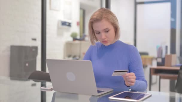 Молода жінка купує онлайн на ноутбуці в офісі - Кадри, відео