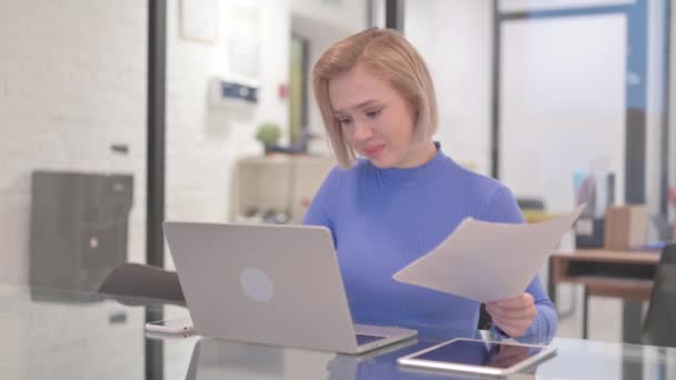 Jonge vrouw voelt zich van streek tijdens het lezen van contract en het gebruik van laptop - Video