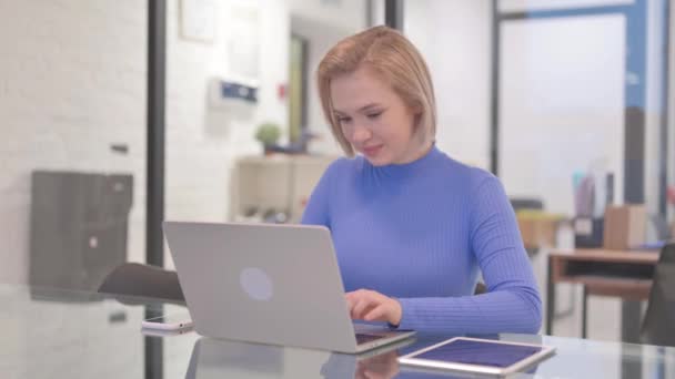 Jonge vrouw met duimen omhoog tijdens het werken op laptop in kantoor - Video
