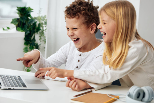 Niños felices estudiando en línea en el hogar usando computadoras portátiles en una acogedora sala de estar - Foto, imagen