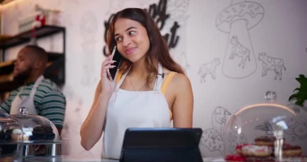 Cafe, tablet and woman talking in phone call for online order for food delivery or takeaway in small business. Virtual, client and contact us at coffee shop with barista at cashier with communication. - Materiaali, video
