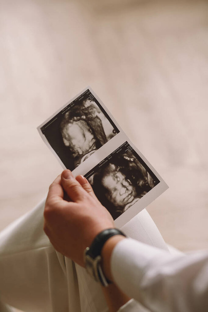 Közelkép egy terhes nőről és a férjéről, akik az ultrahangos képet tartják. Másold le a helyet a szövegnek. A boldog szülőség fogalma - Fotó, kép