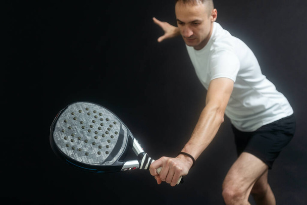 Joueur de tennis Padel avec raquette entre les mains. Paddle tennis, sur fond noir. Photo de haute qualité - Photo, image
