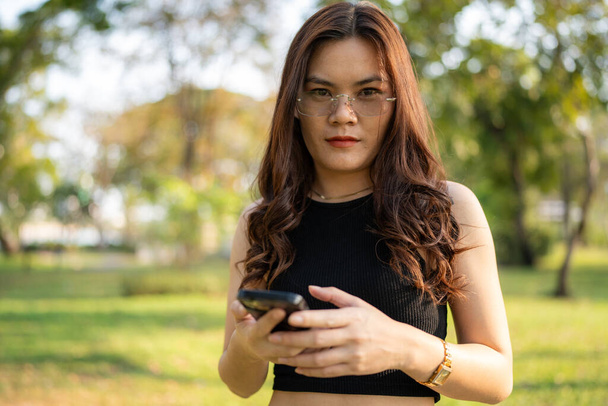 Деловые случайные азиатская женщина использовать смартфон в городском парке заката света онлайн деловое общение - Фото, изображение