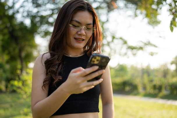 Affari casual asiatico donna uso smartphone in città parco tramonto luce online business comunicazione - Foto, immagini