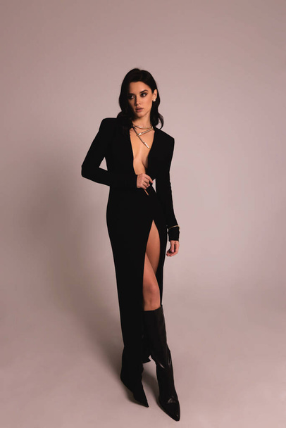 fashion photo of beautiful woman with dark hair in luxurious sexy black dress posing in the studio - Fotó, kép