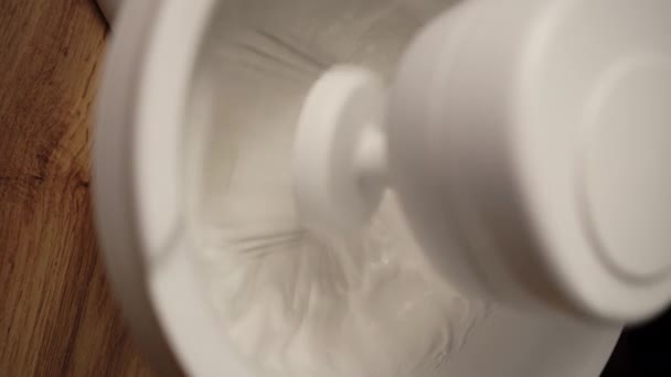Séf főzés nehéz tejszínhab keverve stand mixer, közelkép. Tejszínhab vagy tojás összekeverése habverővel ellátott állványkeverőben. Felülnézet - Felvétel, videó