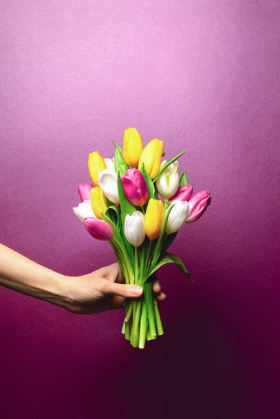 Vista frontal del ramo de tulipanes que se sostiene en una mano, el concepto festivo se burla de un espacio para un texto de saludo - Foto, imagen