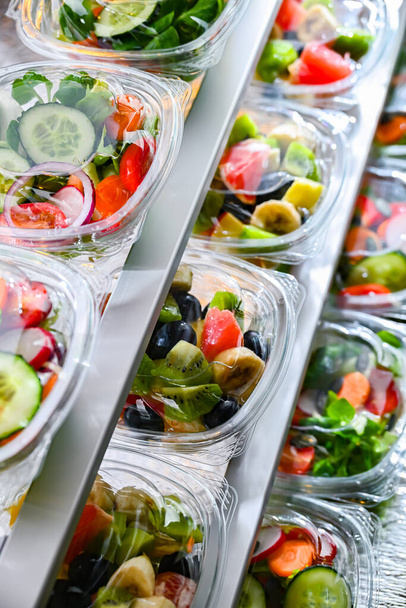 Пластикові коробки з попередньо упакованими фруктово-овочевими салатами, виставлені на продаж в комерційному холодильнику
 - Фото, зображення