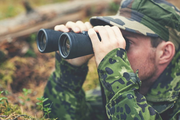 young soldier or hunter with binocular in forest - Foto, afbeelding