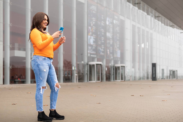 Mulher trans geração Z em pé na rua usando celular, espaço de cópia. Foto de alta qualidade - Foto, Imagem